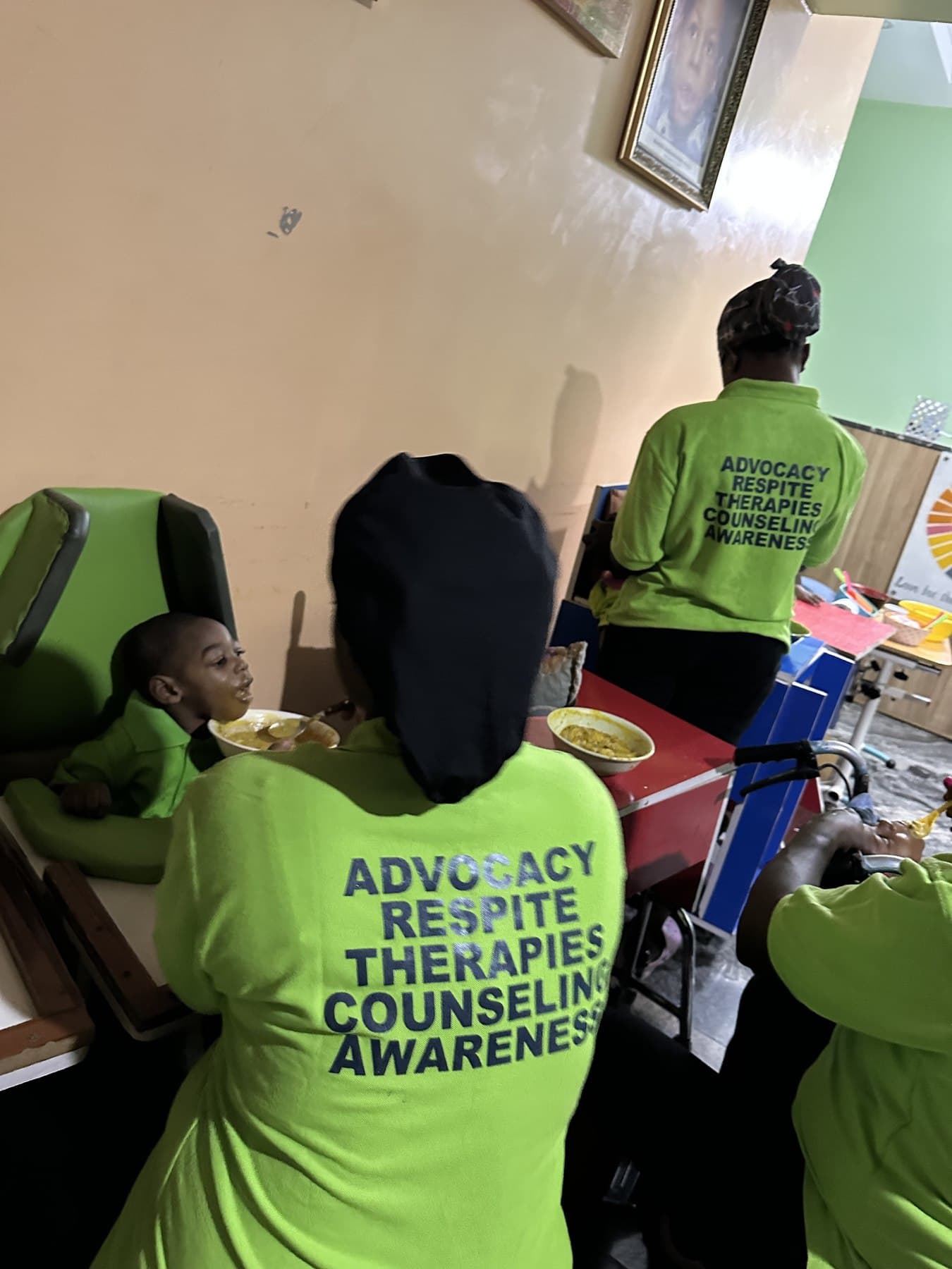 SECHILD caregivers in Advocacy, Respite, Therapies, Counseling, and Awareness shirts feeding a child