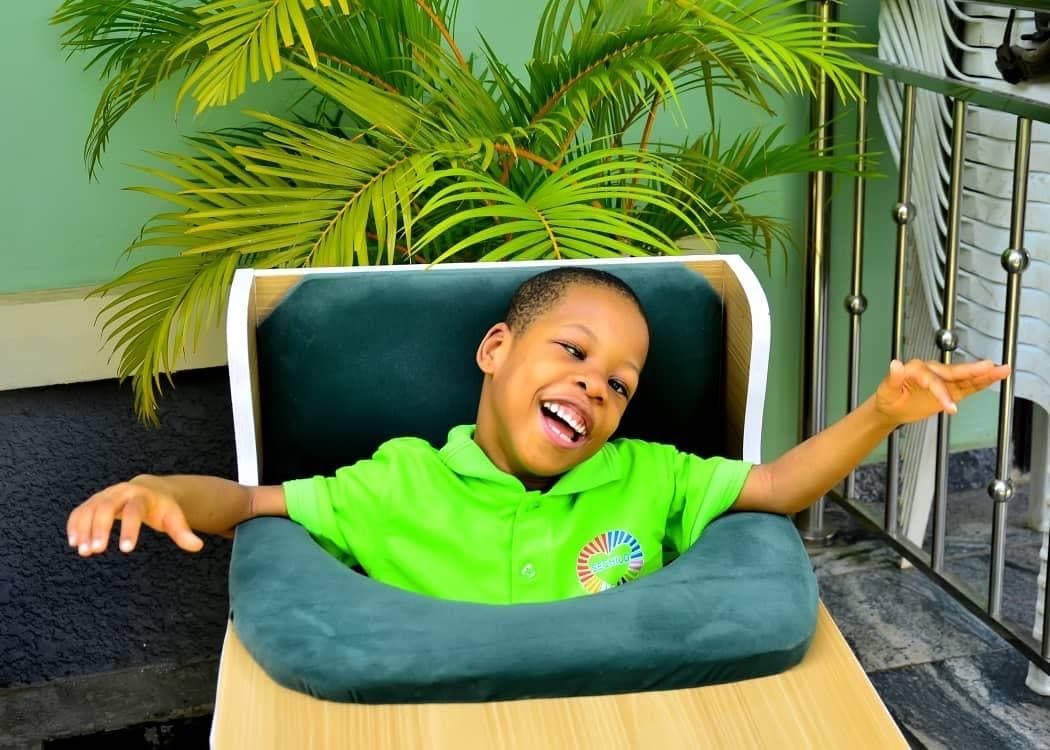 A child at SECHILD's center laughing with arms open wide
