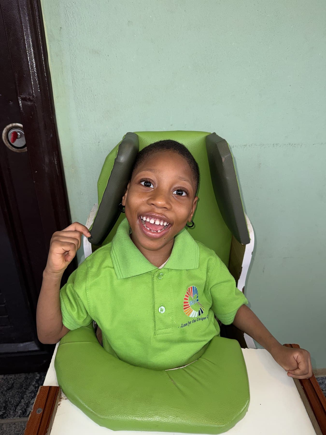 A child at SECHILD's center smiling with a raised fist