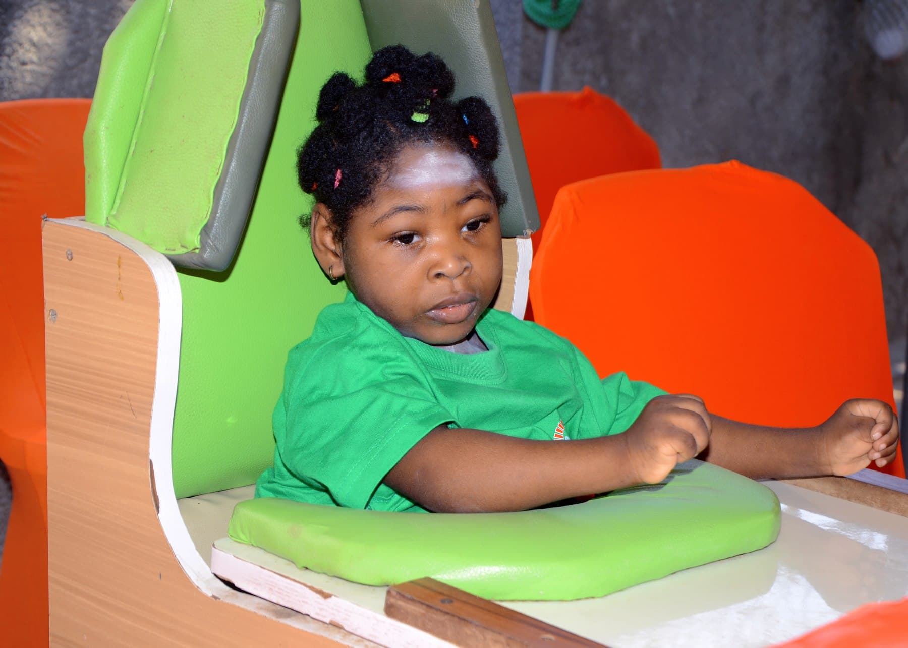 A child seated in an adaptive positioning chair during a therapy session at SECHILD